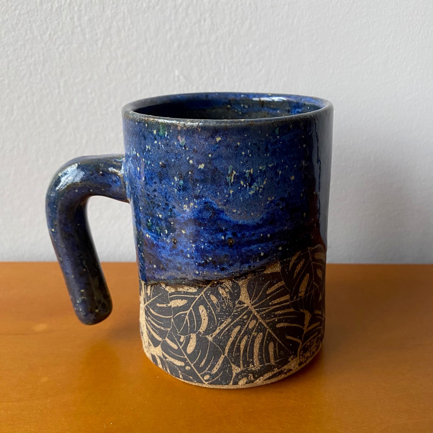 Blue mug with monstera leaf pattern and floating handle